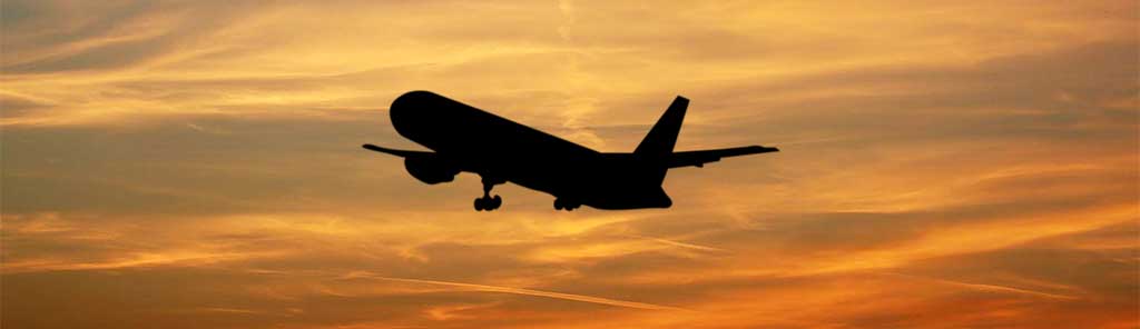 silhouette plane taking off against an orange sky